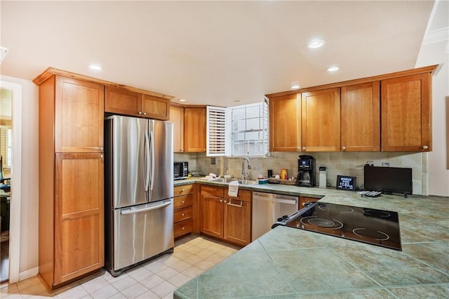 5004-0606 Newlands St, Metairie, LA 70006 - kitchen with light tile patterned floors, a sink, brown cabinetry, stainless steel appliances, and decorative backsplash