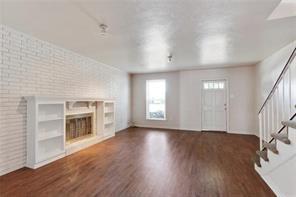 5004-0606 Newlands St, Metairie, LA 70006 - unfurnished living room featuring brick wall, a fireplace, stairway, and wood finished floors