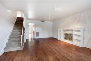 5004-0606 Newlands St, Metairie, LA 70006 - unfurnished living room with visible vents, brick wall, a fireplace, stairway, and wood finished floors