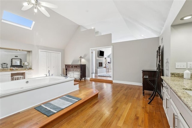 405 14th St, New Orleans, LA 70124 - full bathroom featuring vanity, ceiling fan, a skylight, a garden tub, and wood finished floors