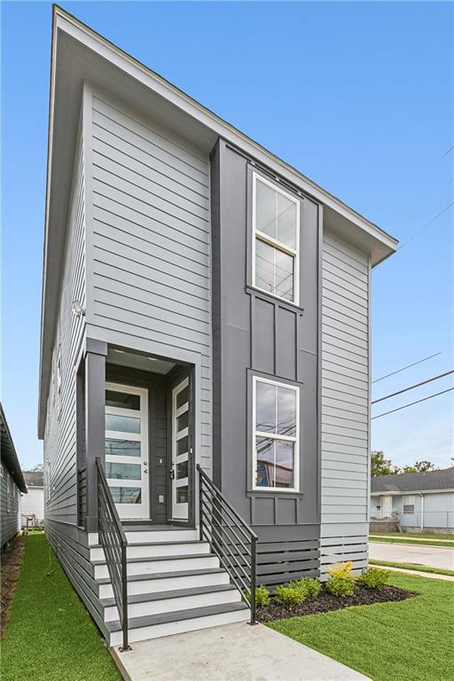 3501-03 Hamburg St, New Orleans, LA 70122 - kitchen featuring stainless steel appliances, a sink, a kitchen island with sink, light wood finished floors, and light stone countertops