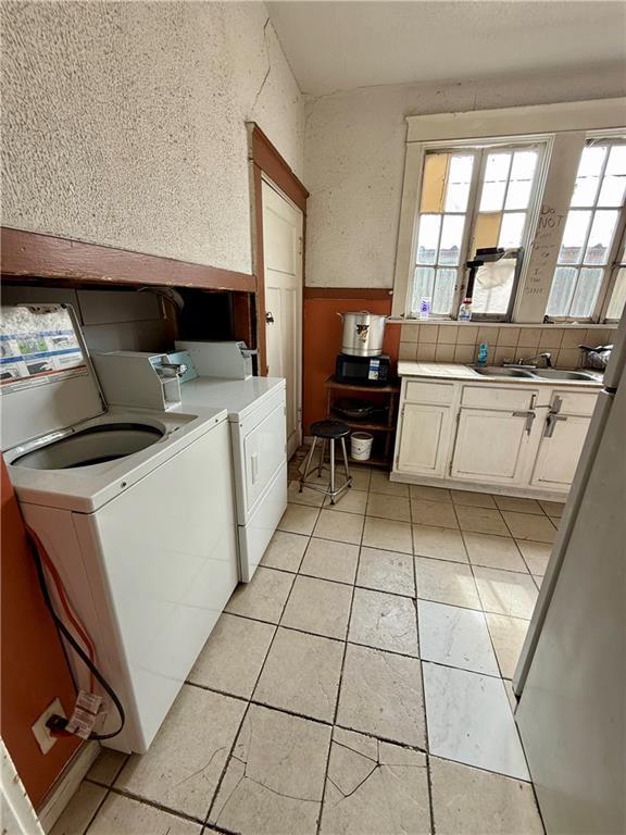 351517 Tulane Ave, New Orleans, LA 70119 - washroom featuring light tile patterned floors, a sink, a textured wall, cabinet space, and washer and clothes dryer
