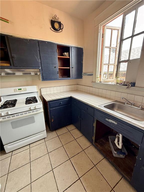 351517 Tulane Ave, New Orleans, LA 70119 - kitchen featuring open shelves, white range with gas stovetop, under cabinet range hood, light tile patterned flooring, and a sink