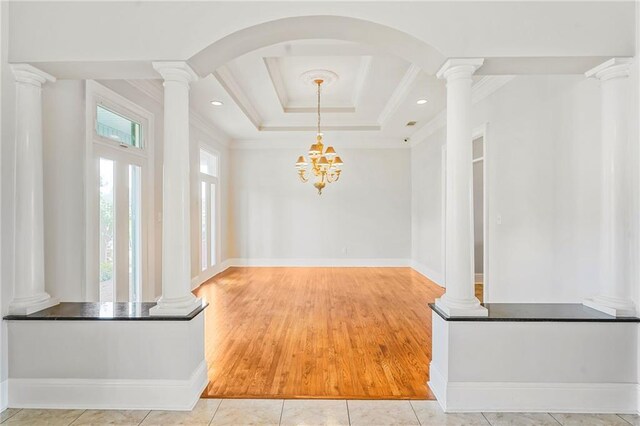 foyer entrance featuring ornate columns, ornamental molding, wood finished floors, and arched walkways