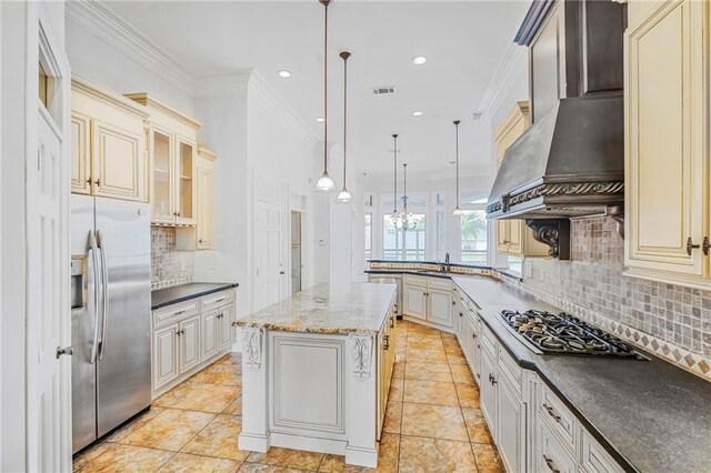 kitchen with stainless steel fridge, cream cabinetry, gas stovetop, backsplash, and a peninsula
