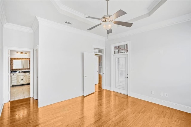 unfurnished bedroom with wood finished floors, ornamental molding, a raised ceiling, and baseboards