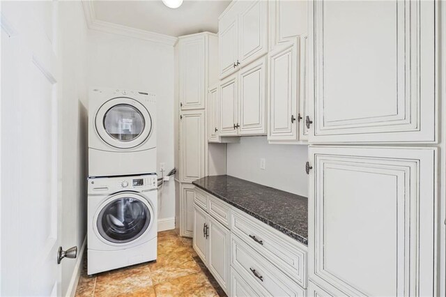 laundry area with stacked washer / drying machine, cabinet space, ornamental molding, and baseboards
