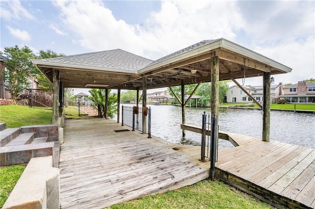 dock featuring a water view, boat lift, and a lawn