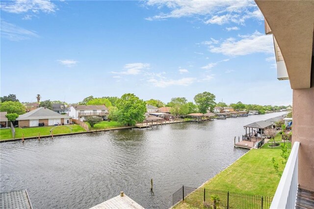water view featuring a boat dock, nearby suburban area, and fence