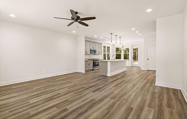 1128 W 19th Ave, Covington, LA 70433 - unfurnished living room with recessed lighting, wood finished floors, a ceiling fan, baseboards, and a sink