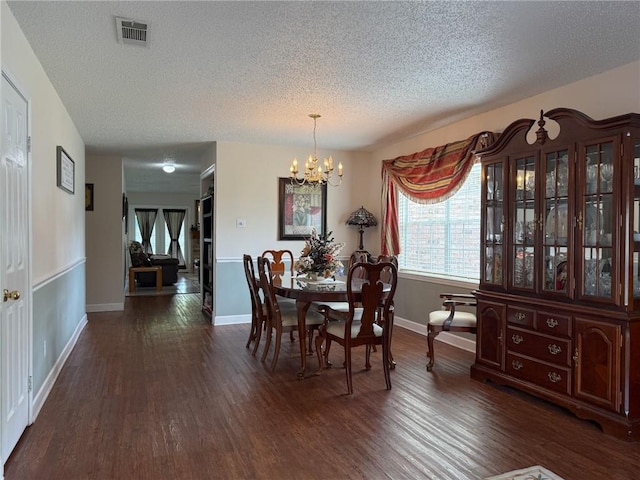 dining room with a textured ceiling, an inviting chandelier, dark wood-style floors, and visible vents