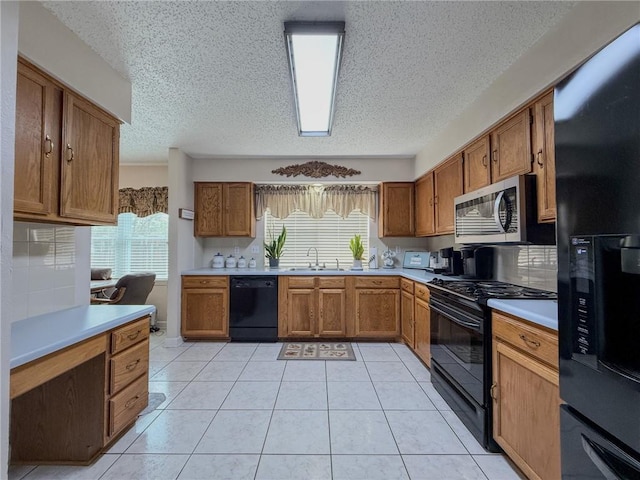 kitchen featuring light countertops, brown cabinets, a sink, and black appliances