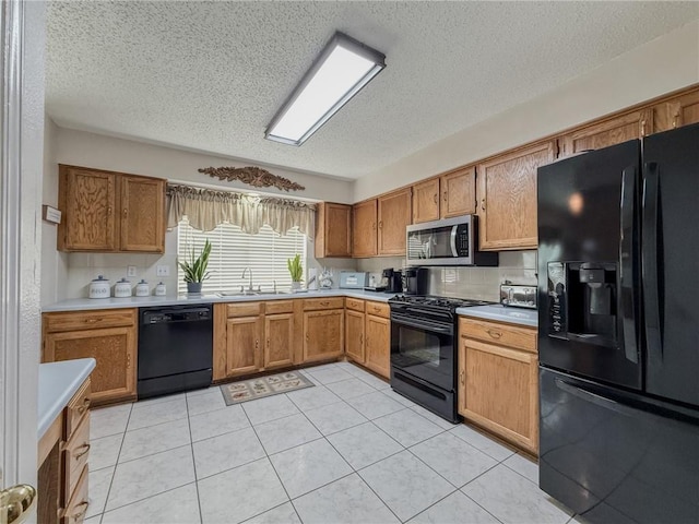 kitchen with a sink, light tile patterned floors, light countertops, and black appliances