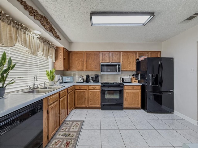 kitchen with visible vents, black appliances, light countertops, a sink, and brown cabinets