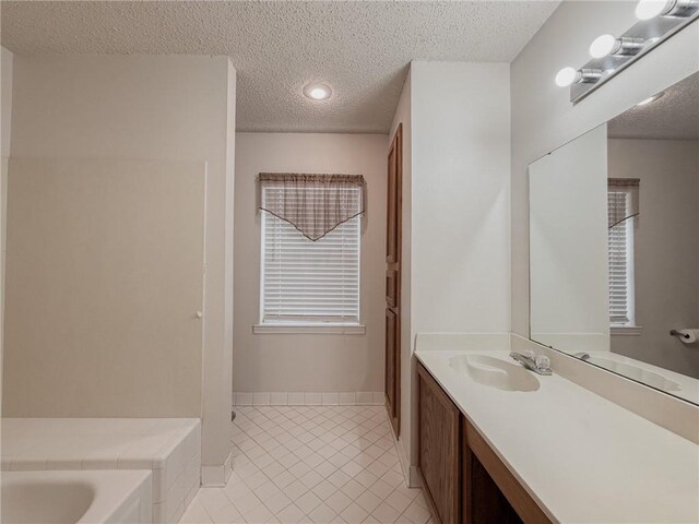 full bathroom featuring a bath, tile patterned floors, vanity, and a textured ceiling