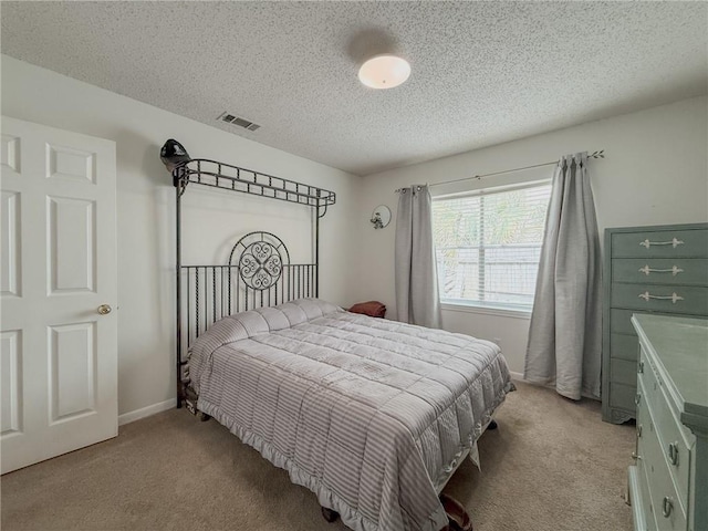 bedroom featuring light carpet, baseboards, visible vents, and a textured ceiling