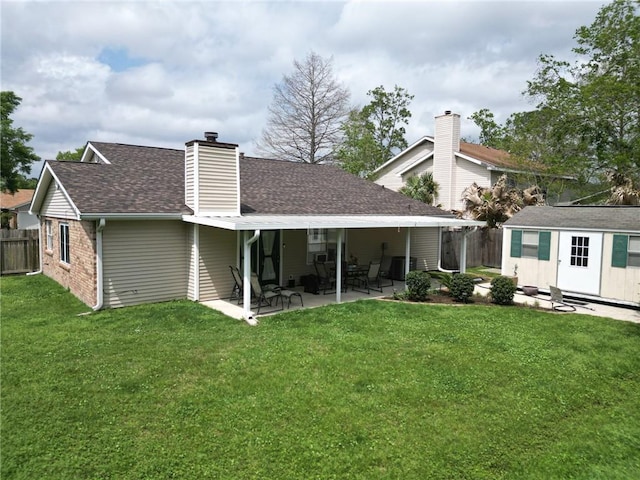 back of property featuring a yard, an outdoor structure, a patio area, fence, and a chimney