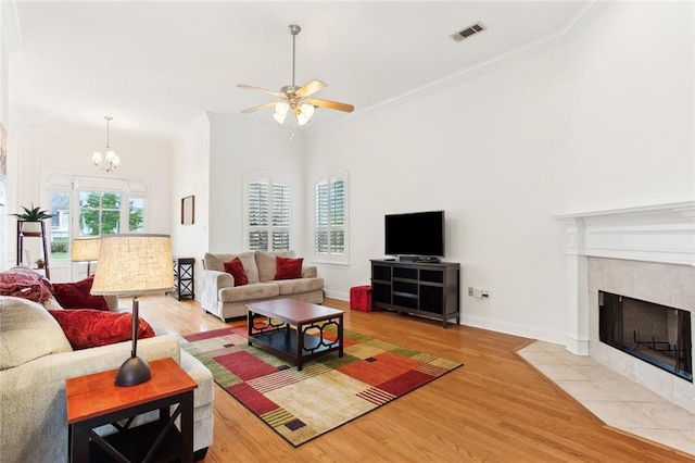 2424 Cours Carson St, Mandeville, LA 70448 - living room with wood finished floors, a ceiling fan, a tile fireplace, a chandelier, and ornamental molding