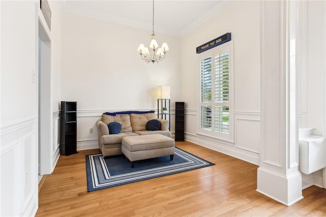 2424 Cours Carson St, Mandeville, LA 70448 - living area featuring a decorative wall, crown molding, light wood-style floors, a chandelier, and wainscoting