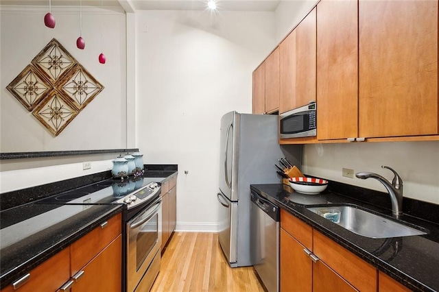 330 Julia St Unit 223, New Orleans, LA 70130 - kitchen featuring stainless steel appliances, light wood finished floors, dark stone countertops, and brown cabinets