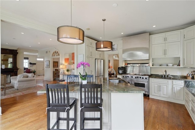 4008 Vendome Pl, New Orleans, LA 70125 - kitchen with high quality appliances, exhaust hood, light wood-style floors, dark stone counters, and a sink