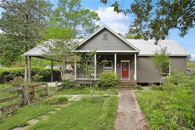 view of front facade with covered porch, fence, and metal roof