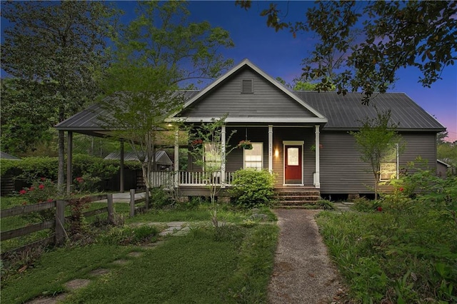 bungalow-style home featuring fence, covered porch, and metal roof