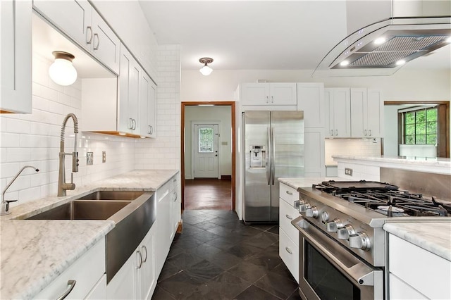 kitchen featuring decorative backsplash, wall chimney exhaust hood, white cabinetry, a sink, and appliances with stainless steel finishes