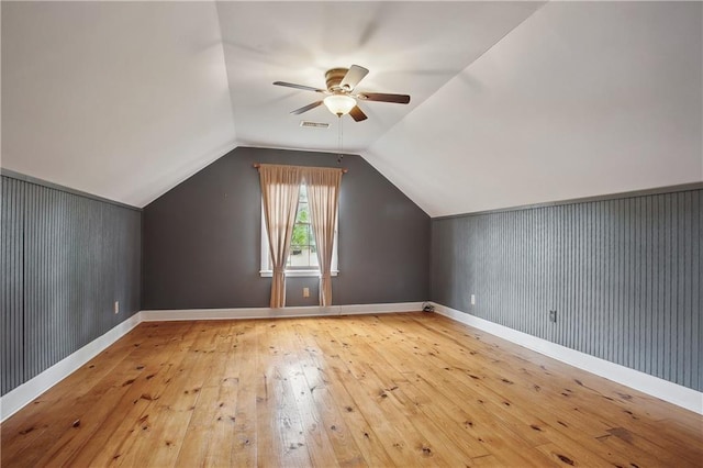 bonus room with wood-type flooring, a ceiling fan, baseboards, and lofted ceiling