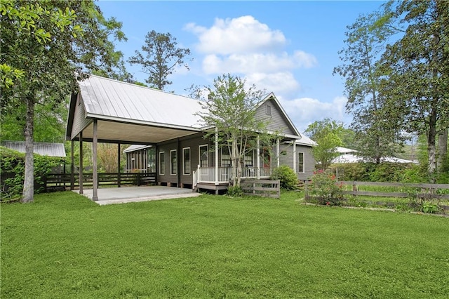 rear view of property featuring fence, a carport, a yard, and metal roof
