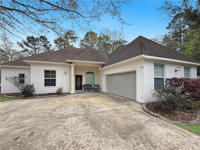 ranch-style home featuring brick siding, a garage, roof with shingles, and driveway