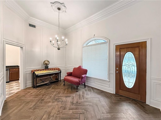 entrance foyer featuring visible vents, crown molding, a decorative wall, and a chandelier