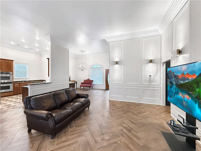 living area featuring an inviting chandelier, recessed lighting, a decorative wall, and ornamental molding