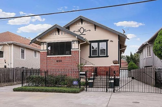 bungalow with stucco siding, a gate, brick siding, and a fenced front yard