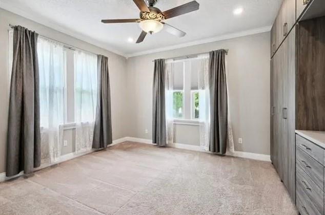 820 Solomon Pl, New Orleans, LA 70119 - unfurnished bedroom featuring multiple windows, light carpet, ornamental molding, baseboards, and recessed lighting