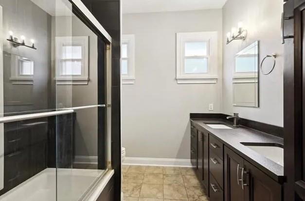 820 Solomon Pl, New Orleans, LA 70119 - full bath with double vanity, baseboards, and bath / shower combo with glass door