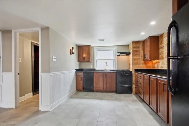 820 Solomon Pl, New Orleans, LA 70119 - kitchen with black appliances, dark countertops, brown cabinetry, wainscoting, and light tile patterned floors