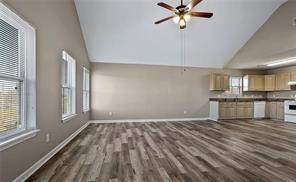 unfurnished living room featuring wood finished floors, high vaulted ceiling, baseboards, and a ceiling fan