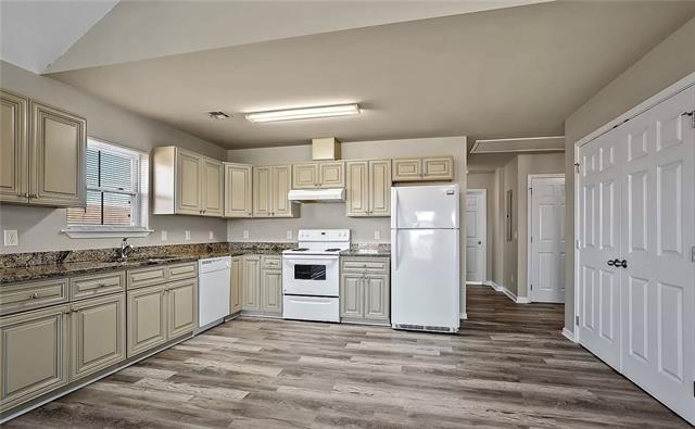 kitchen with under cabinet range hood, white appliances, light wood-style floors, and cream cabinets