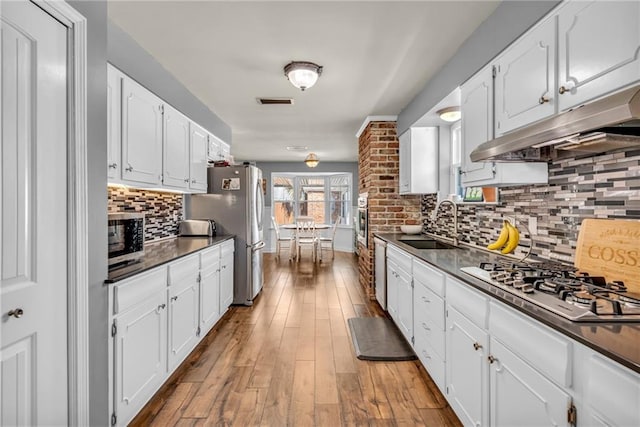 621 Gordon Ave, Harahan, LA 70123 - kitchen with white cabinets, stainless steel appliances, a sink, dark countertops, and under cabinet range hood