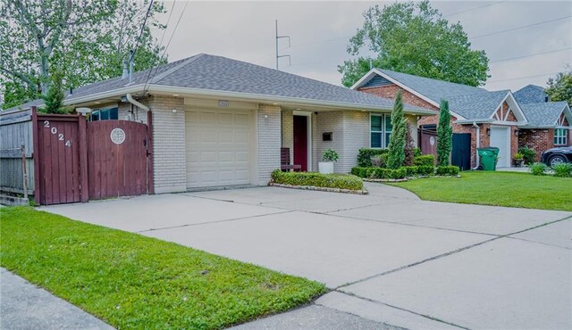 ranch-style home featuring roof with shingles, a front lawn, brick siding, an attached garage, and driveway