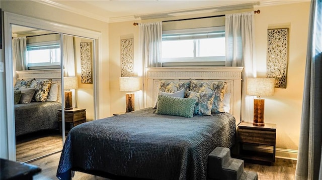 bedroom with baseboards, a closet, ornamental molding, and wood finished floors