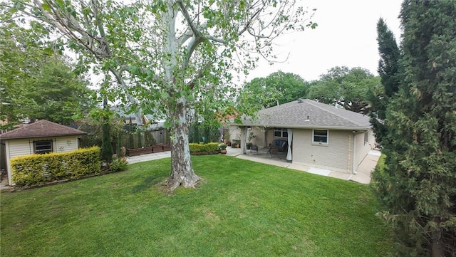 rear view of house with a yard, brick siding, a patio, and roof with shingles