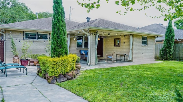 rear view of property with a patio, a shingled roof, fence, and a lawn