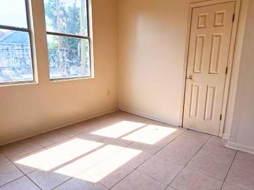212327 Carondelet St, New Orleans, LA 70130 - empty room with light tile patterned floors, baseboards, and a healthy amount of sunlight