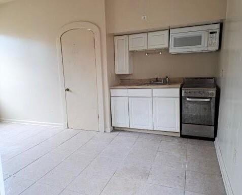 212327 Carondelet St, New Orleans, LA 70130 - kitchen with baseboards, a sink, white microwave, white cabinetry, and stove