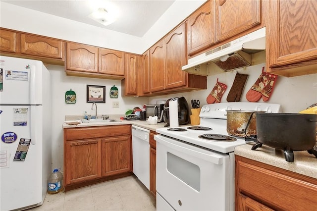 2205 Giuffrias Ave, Metairie, LA 70001 - kitchen with white appliances, light countertops, under cabinet range hood, brown cabinets, and a sink