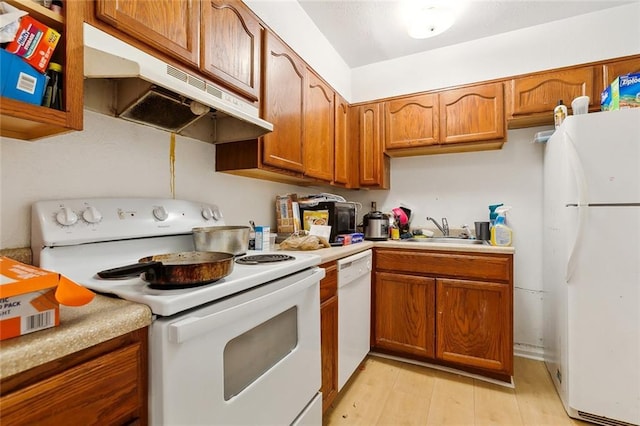 2205 Giuffrias Ave, Metairie, LA 70001 - kitchen featuring white appliances, light countertops, under cabinet range hood, brown cabinets, and a sink