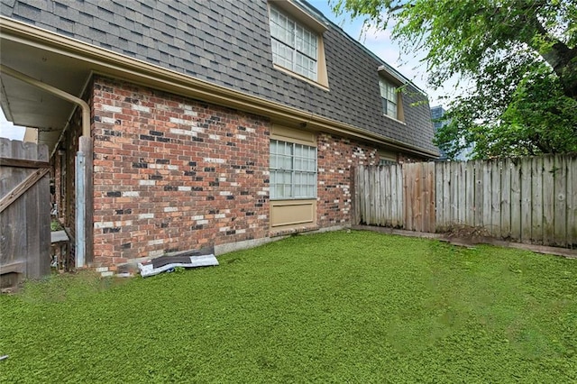 2205 Giuffrias Ave, Metairie, LA 70001 - view of side of property with a yard, a fenced backyard, mansard roof, brick siding, and a shingled roof