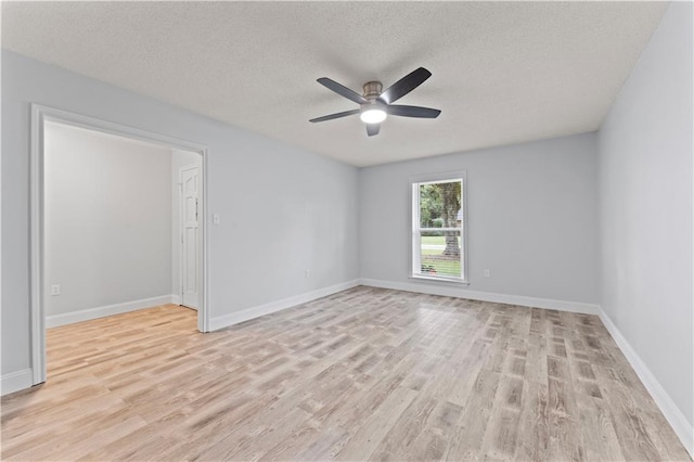 unfurnished room featuring light wood-type flooring, a ceiling fan, a textured ceiling, and baseboards